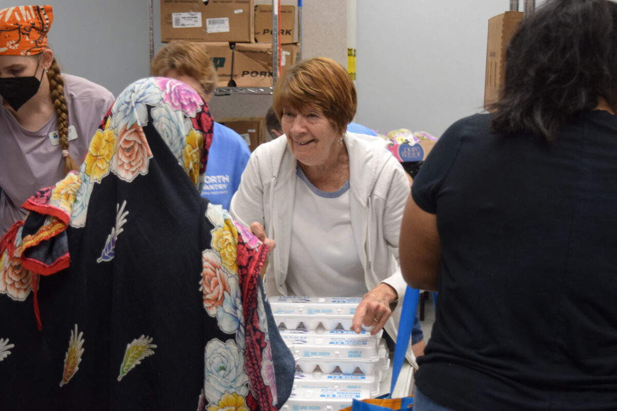 A volunteer smiling and handing food to someone
