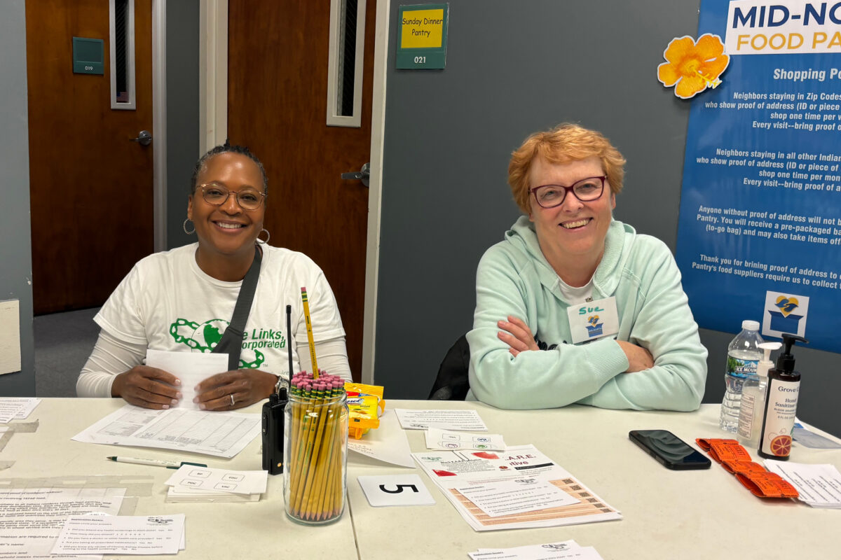 Two smiling volunteers at a checkin desk