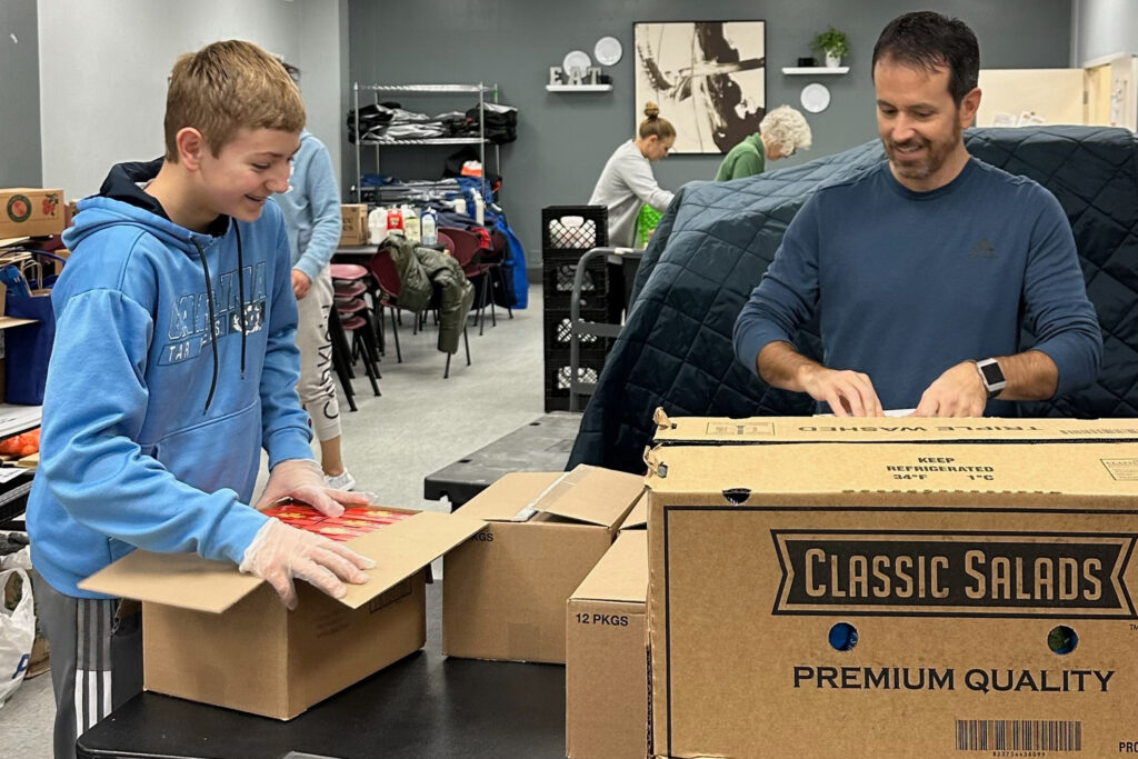 A young adult volunteer helping pack boxes at the food pantry